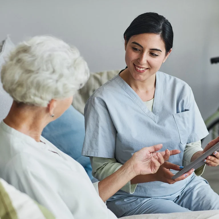 Smiling female caregiver discussing care plan with senior woman using a tablet in Melbourne