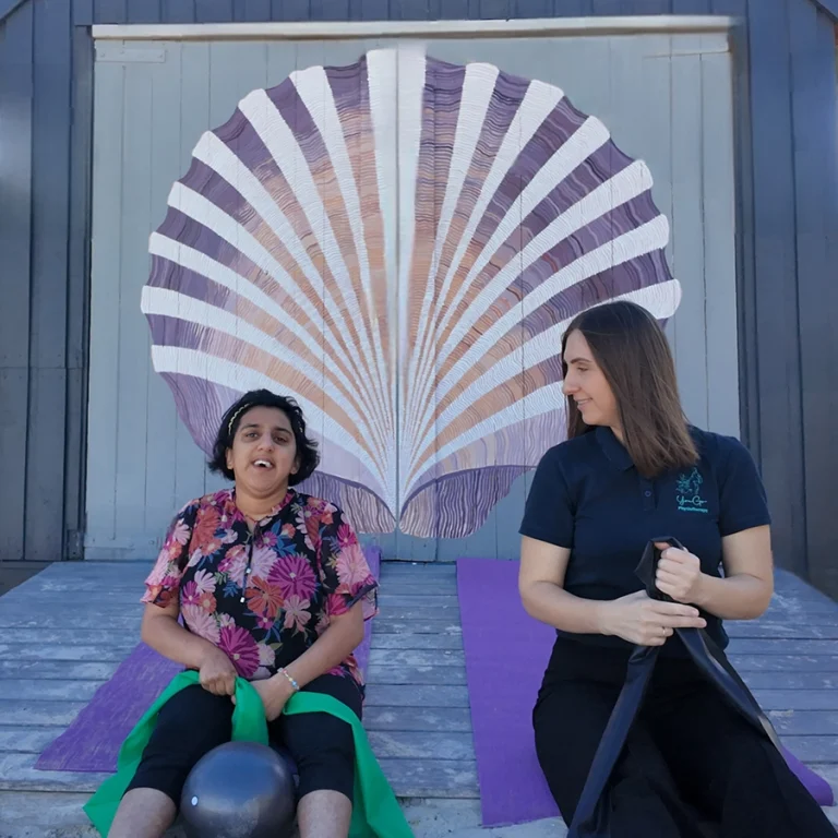 NDIS physiotherapist supporting woman with disability in outdoor exercise session using resistance bands and therapy ball in Melbourne